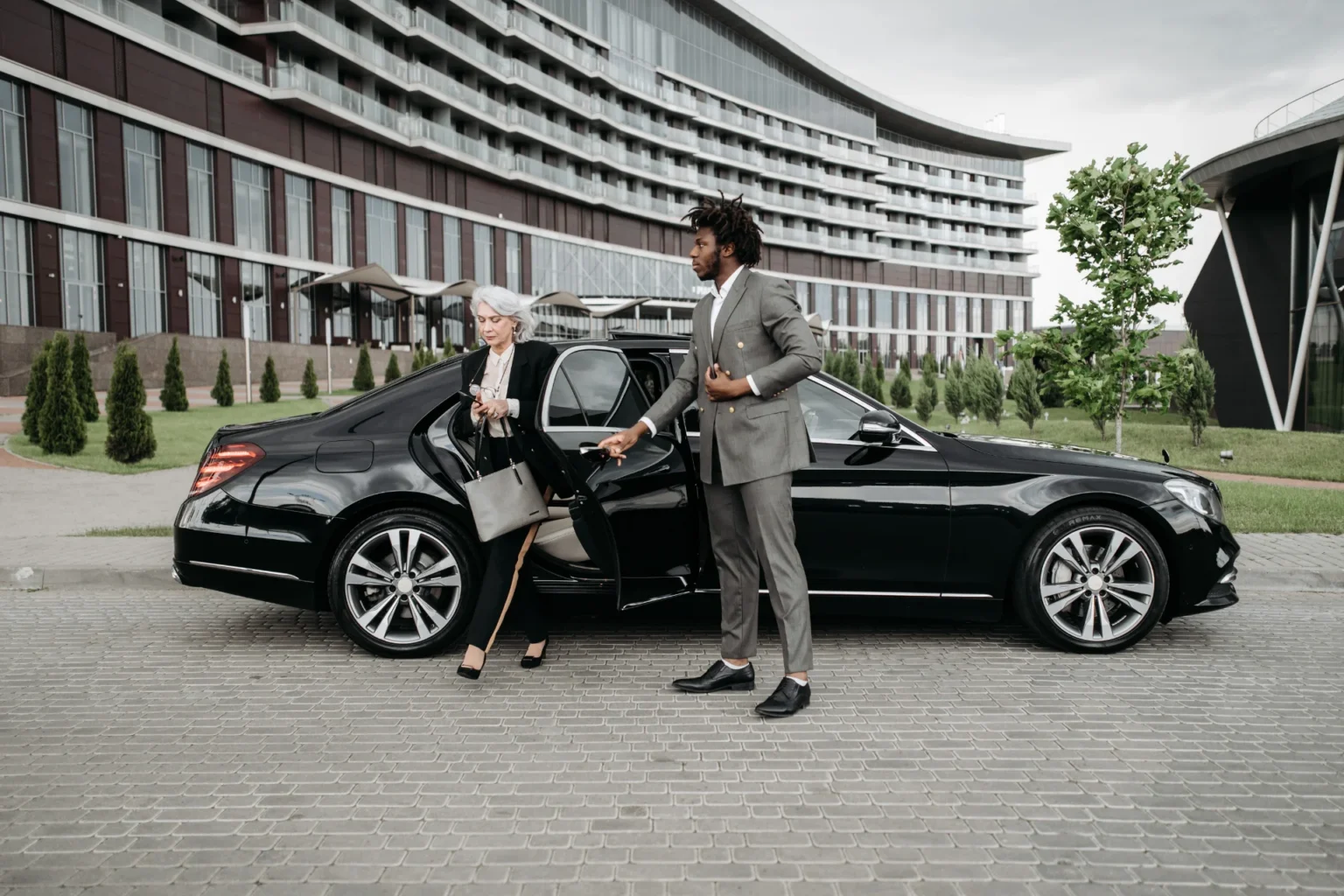 Private chauffeur opening the door of a black Mercedes – private chauffeur service Germany by FlyRide Frankfurt
